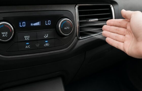 Car dashboard vent being checked while the AC blows warm air