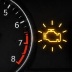 Car dashboard showing a flashing check engine warning light